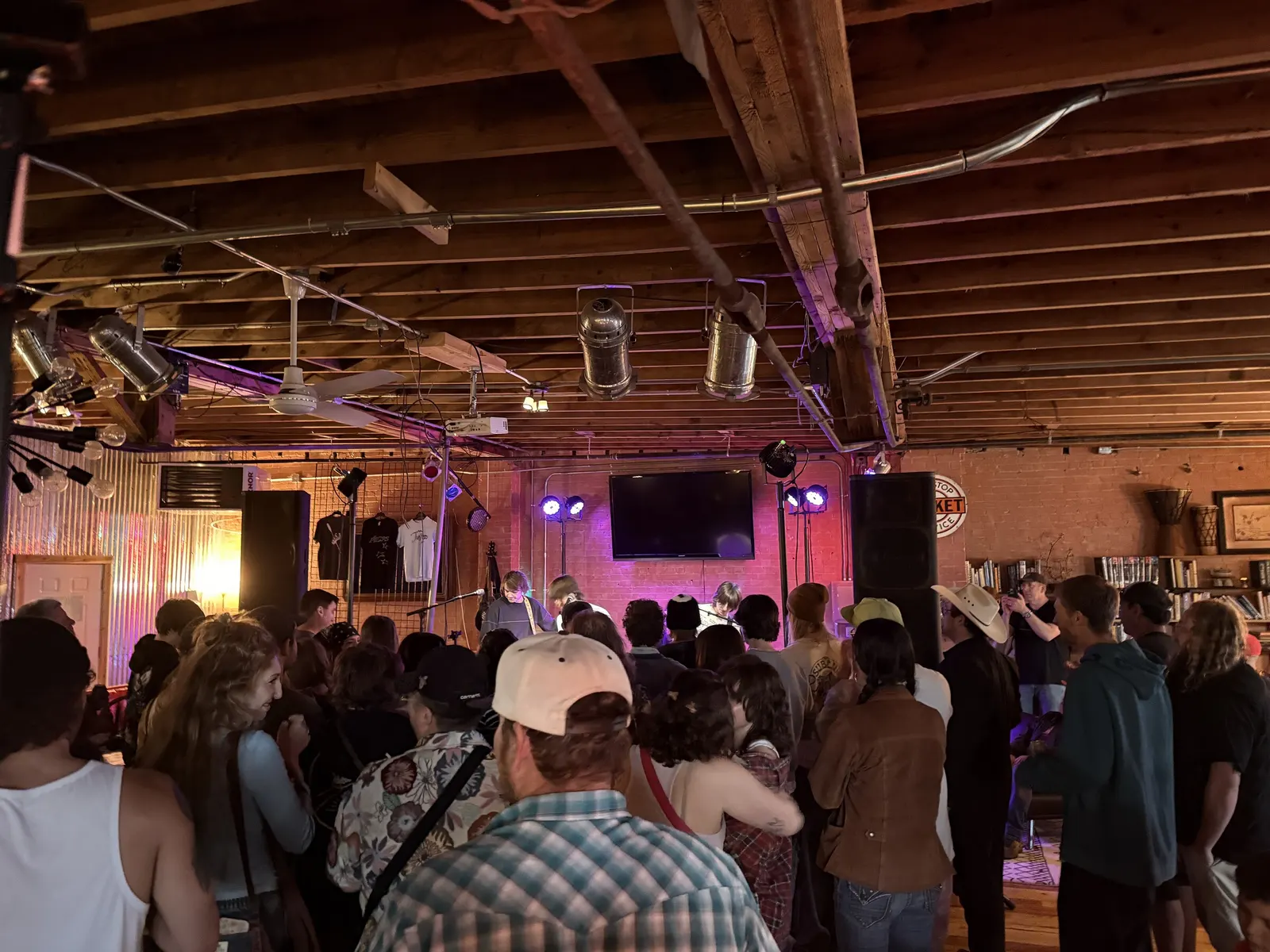 Packed standing crowd in front of a purple-lit stage