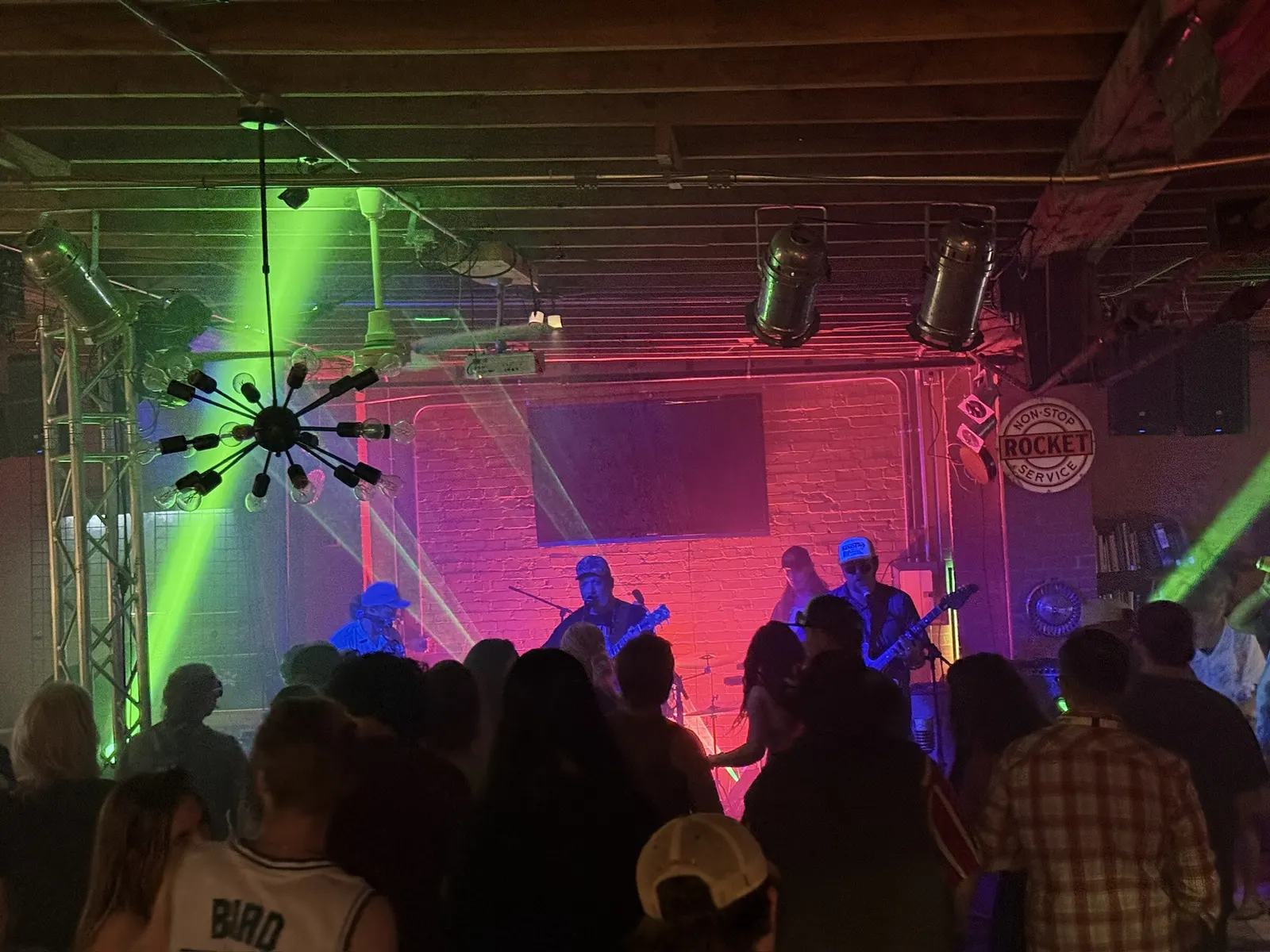 Band under green laser beams with a packed dance floor